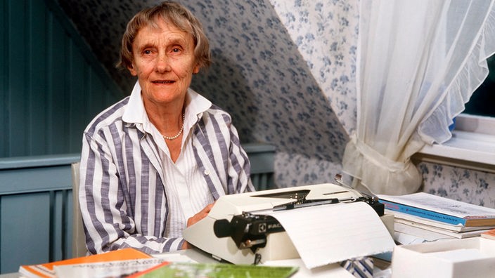 Astrid Lindgren an ihrer Schreibmaschine, im Vordergrund liegen einige ihrer Bücher