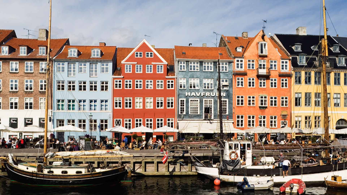 Segelboote liegen im Hafen von Kopenhagen vor bunten Häusern vor Anker.