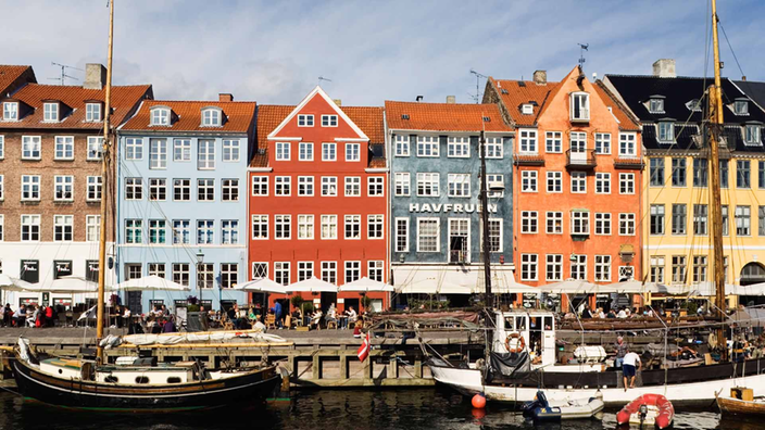 Segelboote liegen im Hafen von Kopenhagen vor bunten Häusern vor Anker. | Bildquelle: Mauritius Images/Alamy Segelboote liegen im Hafen von Kopenhagen vor bunten Häusern vor Anker.