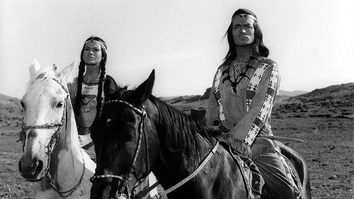 Szene aus dem Film "Winnetou und sein Freund Old Firehand". Die Schauspieler Pierce Brice und Marie Versini sitzen als Indianer auf ihren Pferden und blicken in die Ferne. 