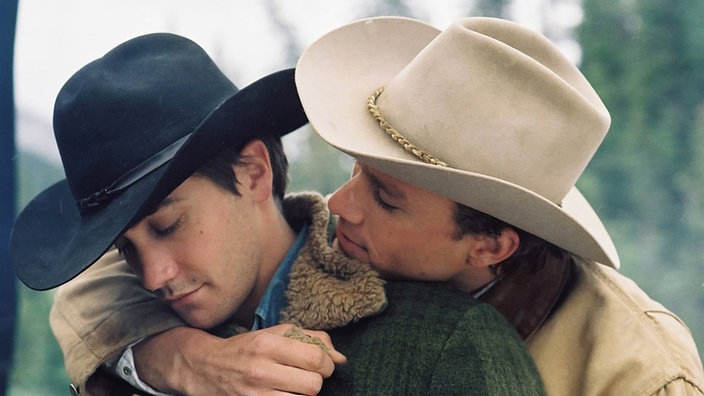Ein Cowboy nimmt einen anderen von hinten in den Arm | Bildquelle: Imago/United Archives Ein Cowboy nimmt einen anderen von hinten in den Arm