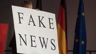 Ein Mann trägt beim politischen Aschermittwoch der baden-württembergischen CDU ein Schild mit der Aufschrift "Fake News"