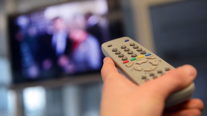Jemand schaltet mit der Fernbedienung den Fernseher ein | Bildquelle: dpa/Caroline Seidel Jemand schaltet mit der Fernbedienung den Fernseher ein