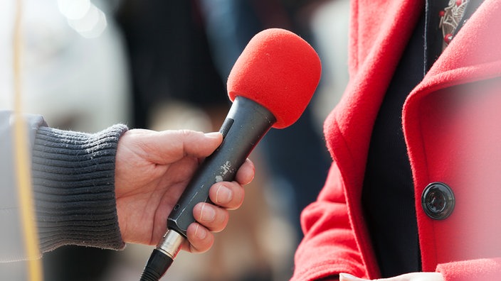 Ein rotes Mikrofon wird in der Hand gehalten | Bildquelle: SWR Ein rotes Mikrofon wird in der Hand gehalten