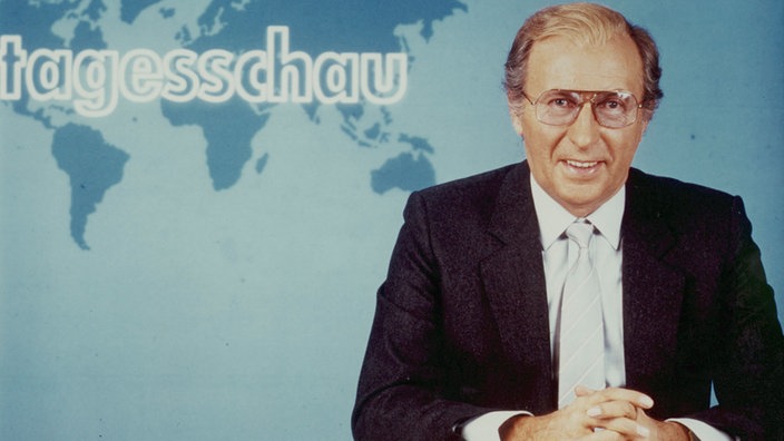 ARD-Nachrichtensprecher Karl Heinz Köpcke sitzt in einem schwarzen Anzug im Tagesschau-Studio (1984). | Bildquelle: NDR ARD-Nachrichtensprecher Karl Heinz Köpcke sitzt in einem schwarzen Anzug im Tagesschau-Studio (1984).