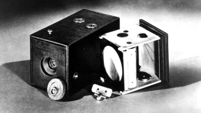 Das schwarz-weiß Foto zeigt die erste Kodak-Kamera. Rechts daneben liegt die Halterung für den Rollfilm, die in die Kamera eingeschoben wurde.