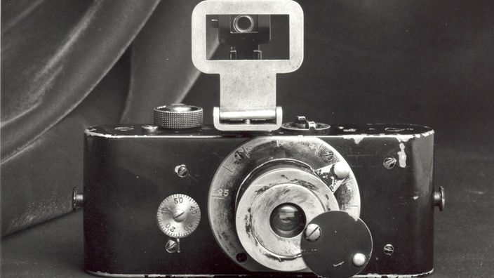 Das Bild zeigt die sogenannte Ur-Leica. Sie war die erste Kleinbildkamera der Welt. Das Modell auf dem Foto zeigt zahlreiche Gebrauchspuren, wie abgeblätterten Lack, Kratzer, Dellen, die belegen, dass dies ein echter Gebrauchsgegenstand war.