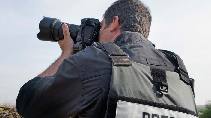 Ein Journalist fotografiert im Krisengebiet | Bildquelle: dpa Picture-Alliance Ein Journalist fotografiert im Krisengebiet