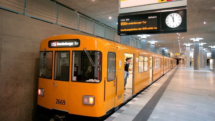 Ein gelber U-Bahnwaggon steht an der Haltestelle Bundestag. Es ist die Linie U55 zum Brandenburger Tor. Ein junger Mann schaut aus einer Tür heraus.