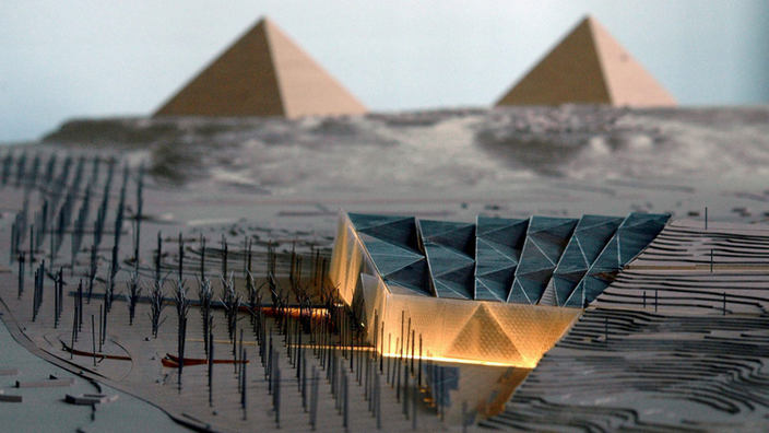 Modell des neuen Museumsgebäudes. Nach rechts ragt das Dach spitz heraus. Im Hintergrund sind zwei Pyramiden zu sehen.