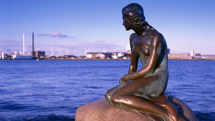 Die Meerjungfrauen-Statue in Kopenhagen ist von der Seite zu sehen. An ihren Beinen hat sie Flossen statt Füße.