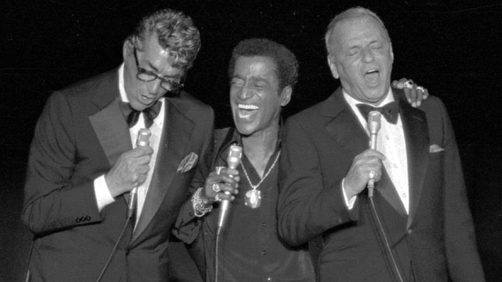 Frank Sinatra, Sammy Davis Junior und Dean Martin stehen in Anzügen nebeneinander und singen