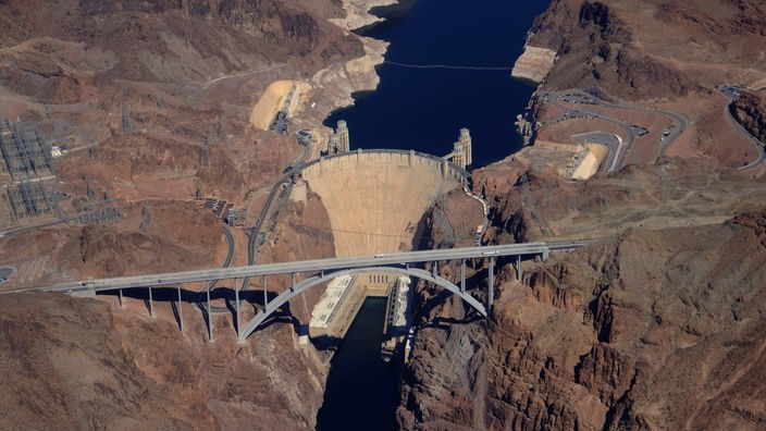 Luftaufnahme eines Stausees mit Staudamm, davor eine Brücke