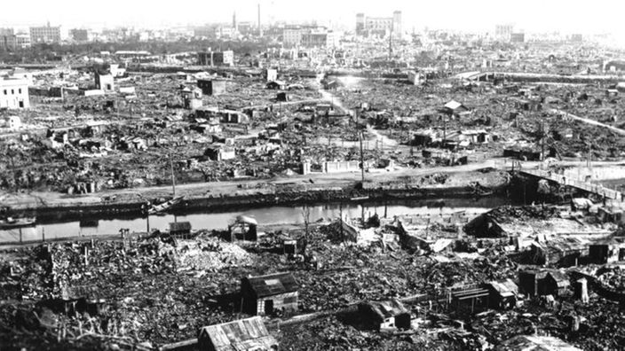 Schwarzweiß-Foto einer völlig zerstörten Stadt. Nur ein paar Ruinen stehen noch.