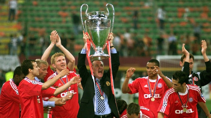 Ottmar Hitzfeld in schwarzem Anzug und Spieler nach dem Gewinn der Champions-League 2001