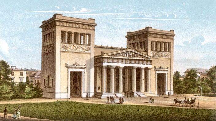 Das Bild des Königsplatzes wird von den sogenannten Propyläen, einem Torbau, bestimmt. In der Mitte ist ein griechisches Tor zu sehen, das rechts und links von zwei Türmen eingerahmt ist. Im Vordergrund sind Passanten, eine Wiese und eine Kutsche dargestellt.