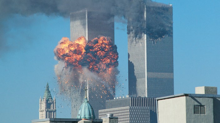 Aus einem Turm der Twin-Towers quillt ein Feuerball, aus dem anderen Turm steigt Rauch auf