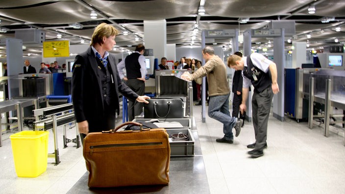 Bei einer Sicherheitskontrolle an einem Flughafen untersucht das Flughafenpersonal die Schuhe eines Passagiers