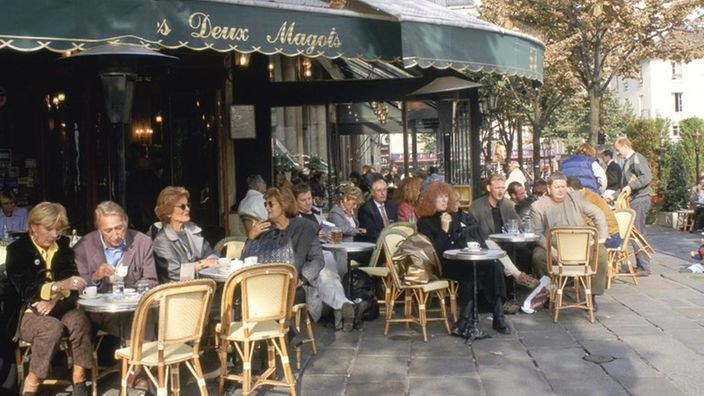 Menschen sitzen draußen vor eonem Café