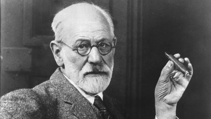 Porträtbild Freuds: weißhaariger, bärtiger Mann mit Nickelbrille, feinem Anzug und einer Zigarre in der Hand. | Bildquelle: akg Porträtbild Freuds: weißhaariger, bärtiger Mann mit Nickelbrille, feinem Anzug und einer Zigarre in der Hand.