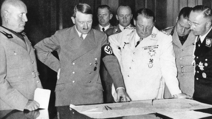 Mussolini, Hitler, Göring und Himmler vor einem Konferenztisch.