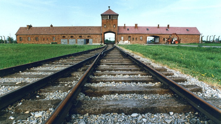 Bahngleise führen auf eine Toreinfahrt im Hintergrund zu. | Bildquelle: WDR/Paul Glaser Bahngleise führen auf eine Toreinfahrt im Hintergrund zu.