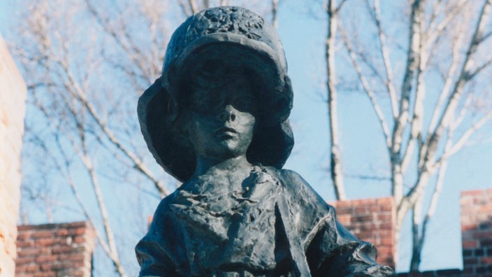 Ein Denkmal zeigt ein Kind in Uniform. Es hat einen Helm auf und ein Gewehr in den Händen.