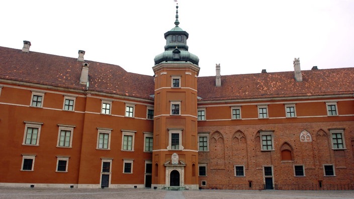 Ein Innenhof wird von beiden Seiten von einem mächtigen Schlossbau aus rotem Stein begrenzt. | Bildquelle: dpa Ein Innenhof wird von beiden Seiten von einem mächtigen Schlossbau aus rotem Stein begrenzt.