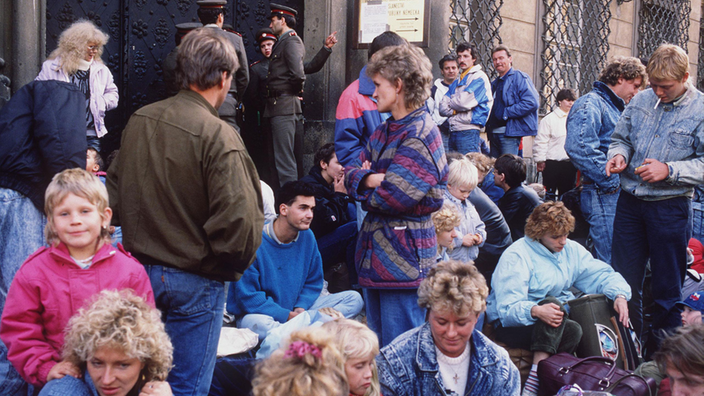 Das Foto zeigt eine Gruppe dicht gedrängter Menschen teils sitzend, teils stehend vor einem historischen Gebäude.