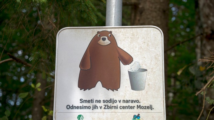 Weißes Warnschild mit braunem Bären und Mülleimer | Bildquelle: picture alliance/imageBROKER Weißes Warnschild mit braunem Bären und Mülleimer