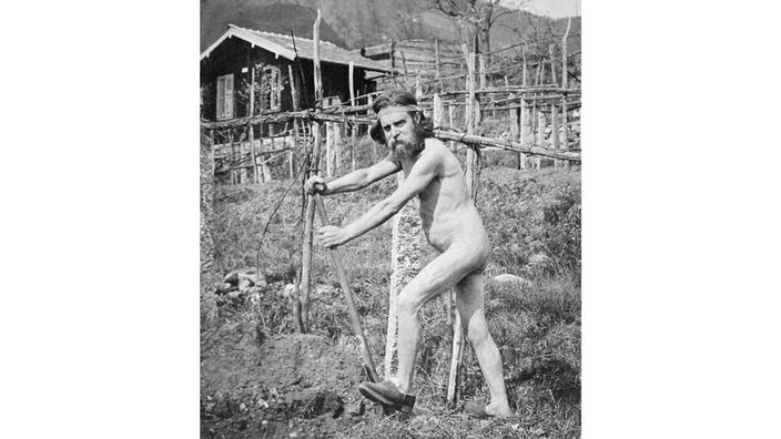 Ein Mann arbeitet nackt auf dem Monte Verità im Garten.