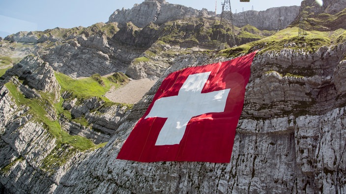 Riesige Schweizer Fahne an einem Berghang | Bildquelle: dpa/Ennio Leanza Riesige Schweizer Fahne an einem Berghang
