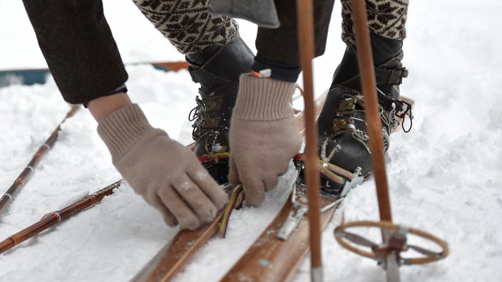 Ein Teilnehmer schließt beim Nostalski-Rennen seine alten Skischuhe