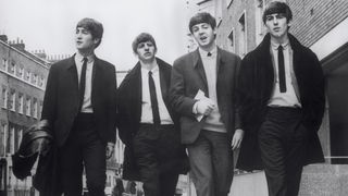 Mitglieder der Popband "The Beatles" John Lennon, Ringo Starr, Paul MacCartney und George Harrison laufen 1964 im Anzug eine Straße entlang.
