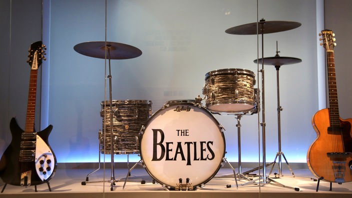 Ein Schlagzeug-Set mit der Aufschrift "The Beatles" und zwei Gitarren stehen auf einer Bühne