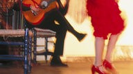 Blick auf Gitarrenspieler und die Beine einer Flamenco-Tänzerin