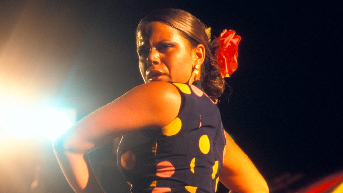 Eine Frau tanzt Flamenco im gepunkteten Kleid.