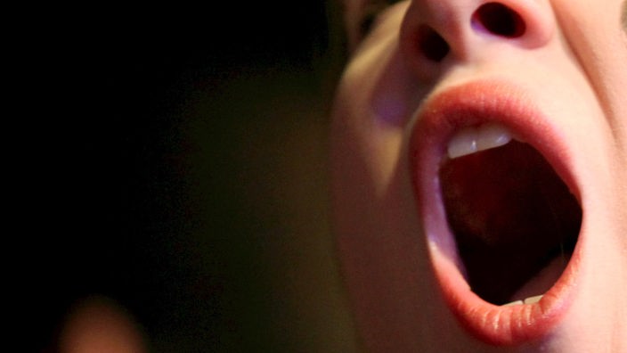 Ein Mädchen reißt den Mund auf.