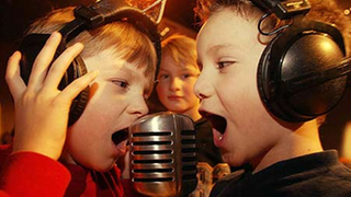 Zwei Kinder singen in ein Mikrofon.