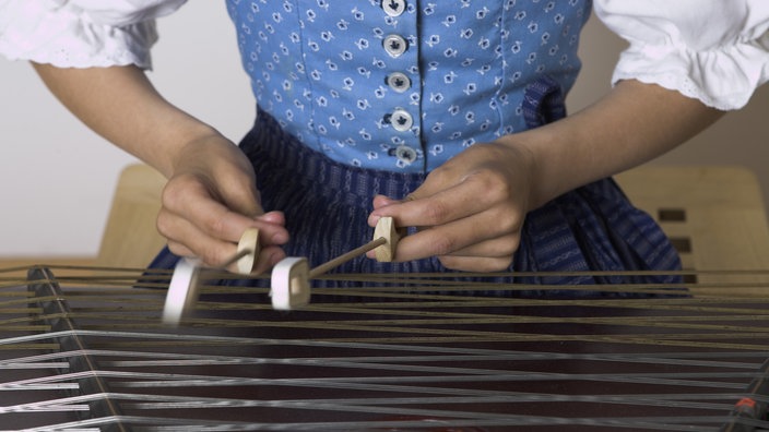 Eine Frau im Dirndlkleid spielt auf dem Hackbrett | Bildquelle: Mauritius Eine Frau im Dirndlkleid spielt auf dem Hackbrett