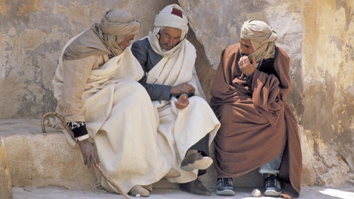 Drei Araber sitzen auf einem Stein und unterhalten sich