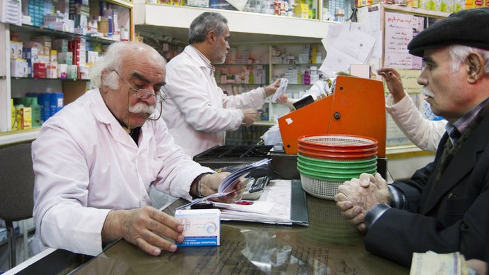 Ein alter Mann kauft ineiner Apotheke in Teheran Medikamente.