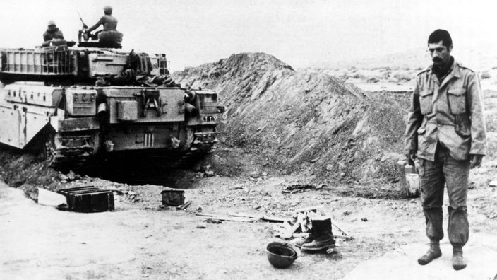 SW-Foto: Ein iranischer Soldat steht auf einem Gebetsteppich neben einem Kampfpanzer. | Bildquelle: Imago SW-Foto: Ein iranischer Soldat steht auf einem Gebetsteppich neben einem Kampfpanzer.