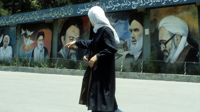 Verschleierte Iranerinnen vor einer Wand mit Porträts verschiedener geistlicher Führer in Teheran, darunter Ayatollah Khomeini (2.v.re.).