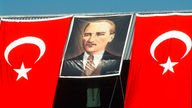 Zwischen zwei türkischen Fahnen hängt ein Porträt von Atatürk