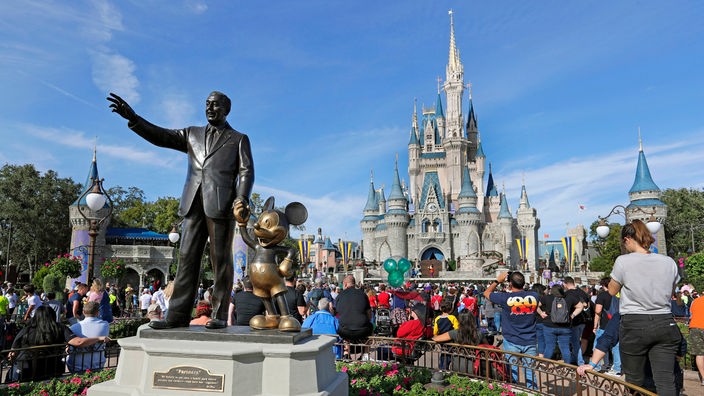 Statue von Walt Disney und Mickey Mouse im Vordergrund. Im Hintergrund Touristen vor dem Cinderella Castle