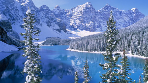 Banff National Park: ein eisblauer See, davor schneebedeckte Bäume, im Hintergrund verschneite Berge.