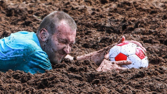 Torwart mit Gesicht und Ball im Schlamm