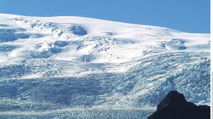 Hinter einer Straße erhebt sich der mächtige Gletscher Vatnajökull.