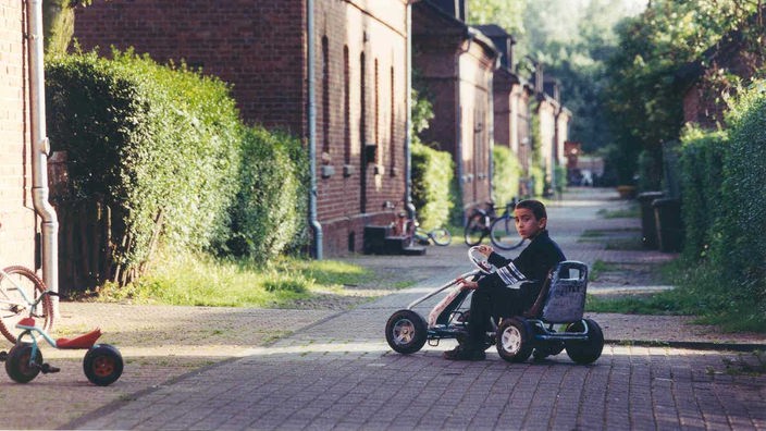 Auf einem Weg in der Oberhausener Siedlung Eisenheim sitzt ein Junge auf einem Kettcar.